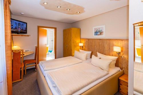 Schlafzimmer mit einem großen weißen Bett und einem Schreibtisch in der Unterkunft Hotel Spitzenhoernbucht in Wolgast