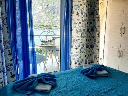 1 dormitorio con cama con sábanas azules y ventana en Blue eye, Prcanj, en Kotor