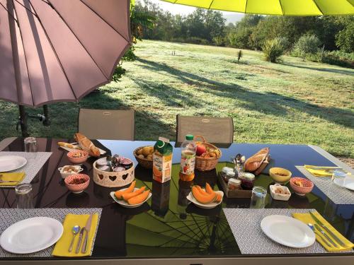 a picnic table with food on it with an umbrella at Location Chambres d'Hôtes Clodeguy No 2 in Saint-Sylvestre-sur-Lot