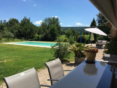 a table and chairs in a yard with a pool at Location Chambres d'Hôtes Clodeguy No 2 in Saint-Sylvestre-sur-Lot