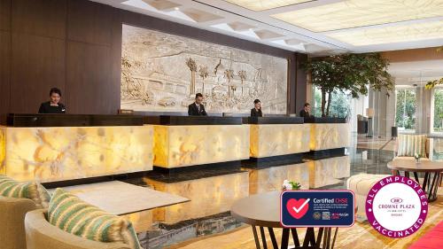 a group of people sitting at a bar in a lobby at Crowne Plaza Bandung by IHG in Bandung