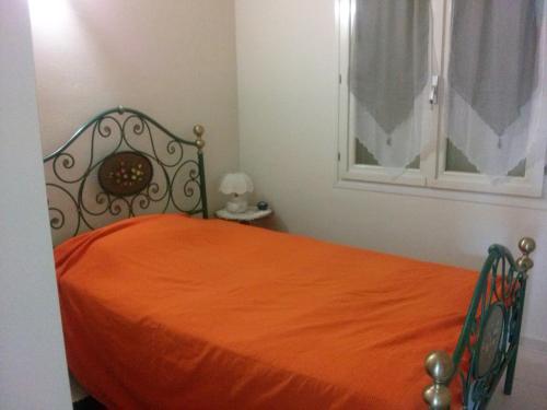 1 dormitorio con cama con colcha de color naranja y ventana en gelso, en Montignano