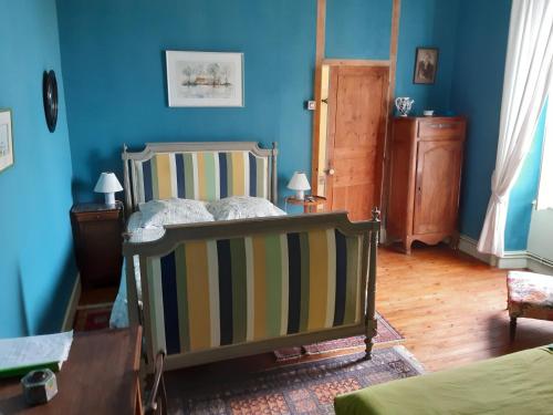 1 dormitorio con 1 cama en una habitación azul en Le Logis, en Les Pineaux