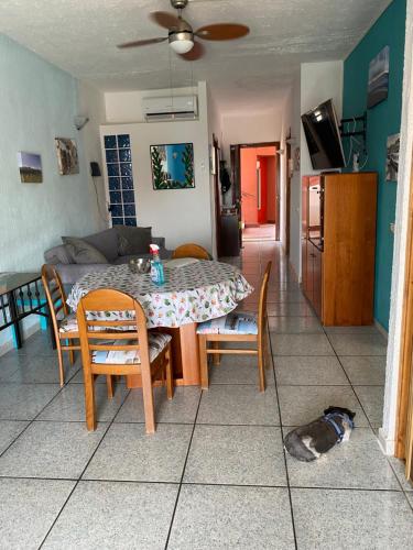 un soggiorno con tavolo, sedie e un cane sul pavimento di Sea View 2 Bedroom Vacation Apartment a Giardini Naxos