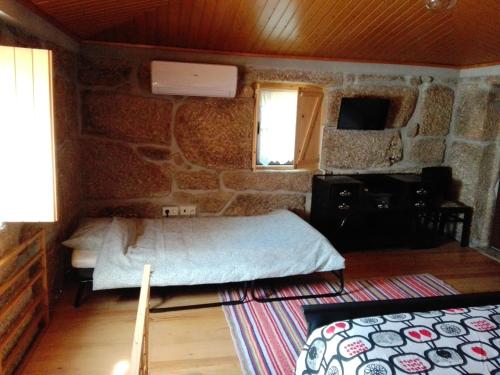 a bedroom with a bed and a stone wall at Lagar da Silveira in Penafiel