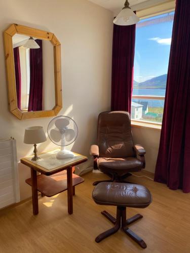 a room with a chair and a table with a mirror at Syðstibær Guesthouse in Hrísey