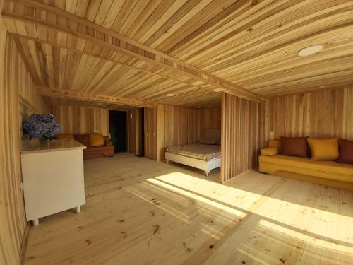 Habitación grande de madera con cama y sofá en Mtirala House, en Khala