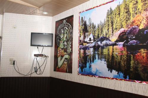 a tv on a wall with two large paintings at Hotel Tip Top in Solan