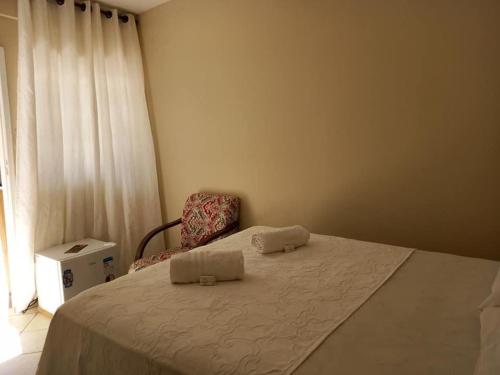 een slaapkamer met een bed met een stoel en een raam bij Hospedagem em Diamantina in Diamantina