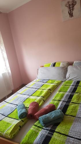 a bed with green and white blankets and pillows on it at Apartmani V&F in Vrnjačka Banja
