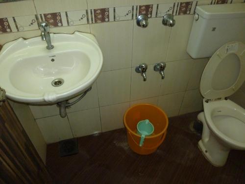 a bathroom with a sink and a toilet and a bucket at Hotel Orient Palace in Mumbai