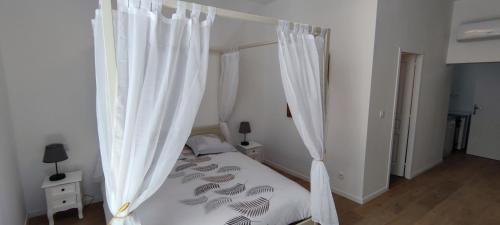 Schlafzimmer mit einem Bett mit weißen Vorhängen in der Unterkunft Soleil Roi - immeuble du 16e siècle en plein coeur de Béziers in Béziers