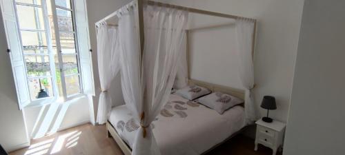 ein Schlafzimmer mit einem Himmelbett und einem Fenster in der Unterkunft Soleil Roi - immeuble du 16e siècle en plein coeur de Béziers in Béziers