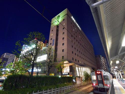 um edifício alto com um comboio à frente em APA Hotel Ogaki Ekimae em Ogaki