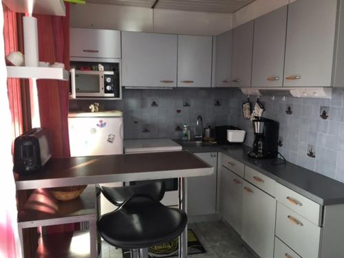 une cuisine avec des armoires blanches et un comptoir noir dans l'établissement APPARTEMENT DE MONTAGNE, à Mijoux