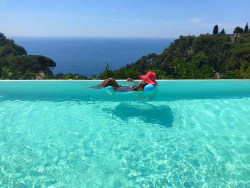 two people laying on a surfboard in the water at L'Olearia Luxury Country Villa in Amalfi Coast in Maiori