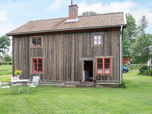 drewniany dom z czerwonymi oknami oraz stołem i krzesłami w obiekcie 4 person holiday home in N SSJ w mieście Nässjö