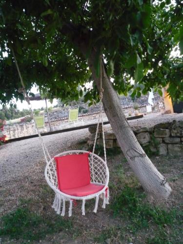 a red chair swing hanging from a tree at Hort de L'Aubert in Cretas