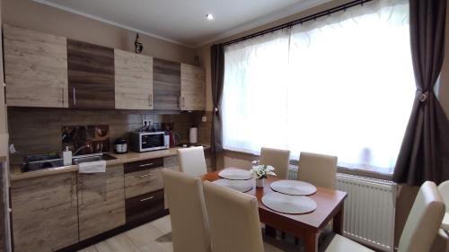 a dining room with a table and chairs and a kitchen at Lux Apartman Velence in Velence