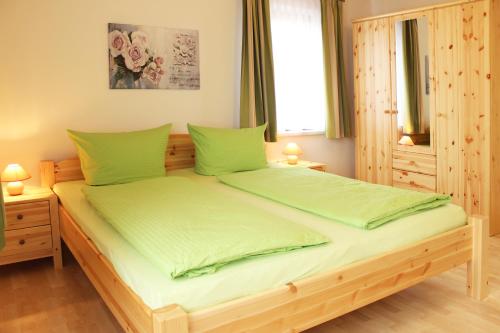 um quarto com uma cama de madeira e lençóis verdes em Ferienhaus Segebrecht em Zirchow