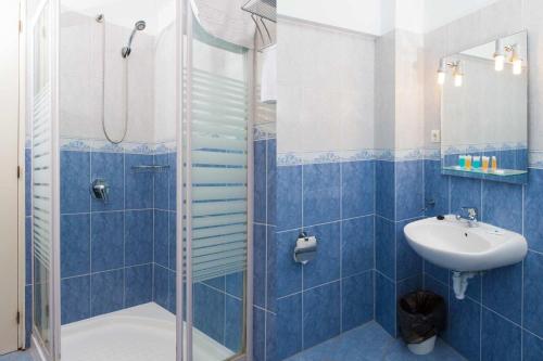 y baño de azulejos azules con ducha y lavamanos. en Apartamentos Mirador 2, en Benidorm