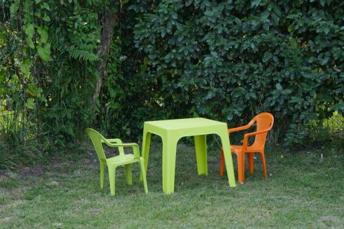 three chairs and a green table in the grass at Jolie Villa neuve, au calme, proche forêt / Bisca in Biscarrosse