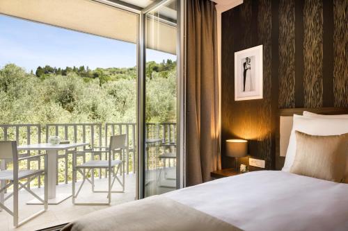 a bedroom with a bed and a balcony with a table and chairs at Remisens BEL MORETTO - Hotel Metropol Annexe in Portorož