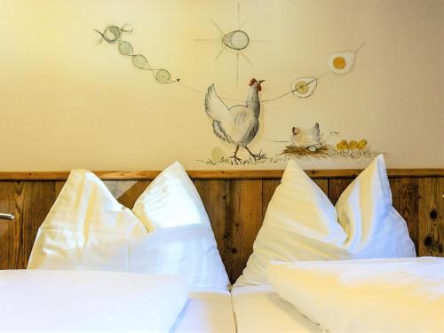 a bed with white pillows and a chicken on the wall at Alpengasthof Hochsöll in Söll