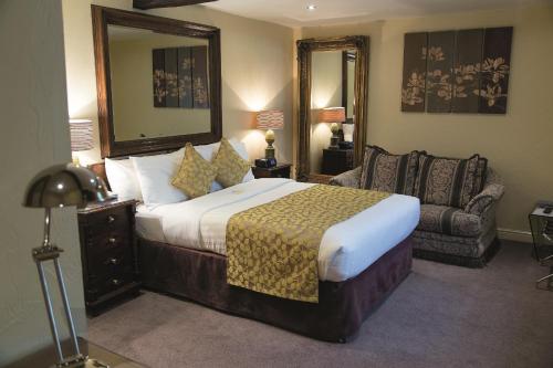 a bedroom with a bed and a chair and a mirror at Best Western Premier Doncaster Mount Pleasant Hotel in Doncaster