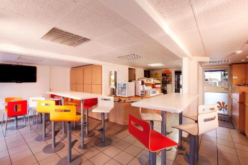 - une cuisine avec des tables et des chaises colorées dans une chambre dans l'établissement Premiere Classe Chelles, à Chelles