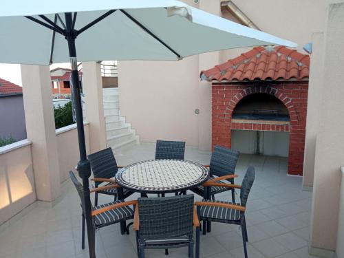 una mesa y sillas con una sombrilla en el patio en Apartments Antonio, en Trogir