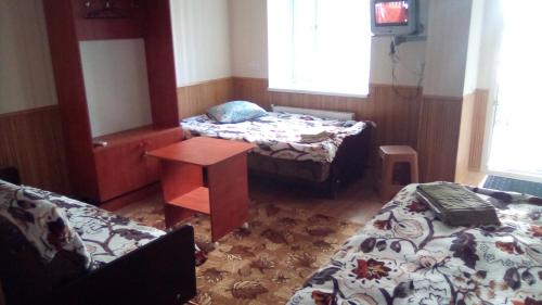 a room with two beds and a table and a desk at 1-я Слободская, 17А, угол проспекта Центрального, 3 дивана, Wi-Fi, отдельный вход. in Mykolaiv