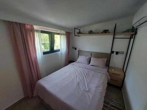 a small bedroom with a bed and a window at Panorama Apartments in Herceg-Novi