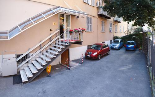 an apartment building with a staircase and cars parked in a parking lot at Hotel Boccascena in Genoa
