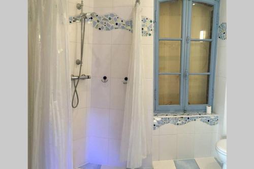 La salle de bains est pourvue d'une douche et d'une fenêtre bleue. dans l'établissement Romantic house - entrance to the medieval castle, à Carcassonne