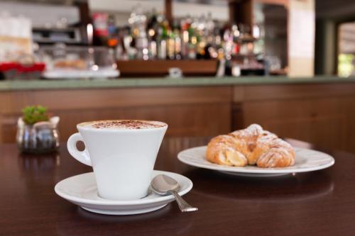 a cup of coffee and two croissants on a table at Hotel Belvedere in Porto SantʼElpidio