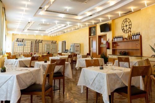 un restaurante con mesas y sillas con mantel blanco en Hotel Belvedere, en Porto SantʼElpidio