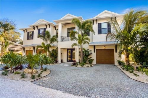 a large white house with palm trees in front of it at Our Great Escape home in Anna Maria
