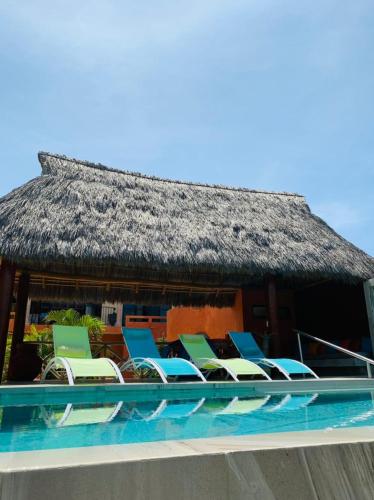 a group of chairs and a building with a roof at Villa La Joya in Barra de Navidad