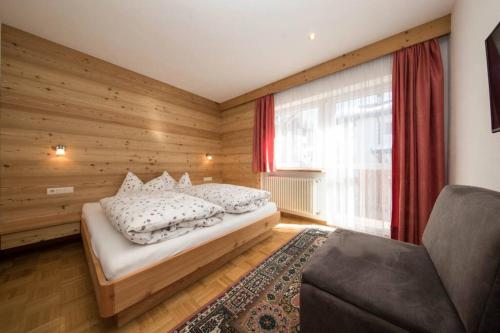 1 dormitorio con cama, ventana y sofá en Chalet Merisana en Selva di Val Gardena