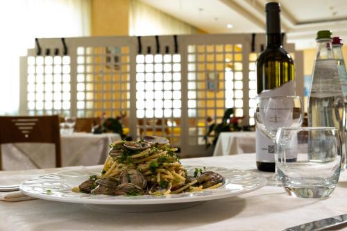 a plate of pasta on a table with a bottle of wine at Hotel Belvedere in Porto SantʼElpidio