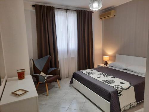 ein Schlafzimmer mit einem Bett, einem Stuhl und einem Fenster in der Unterkunft Casa Vacanze le Palme Netine in Noto