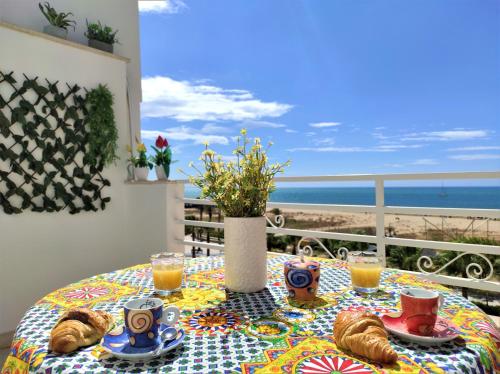 een tafel met eten en drinken en uitzicht op het strand bij MADAGÌ Beachfront Apartments in Pozzallo