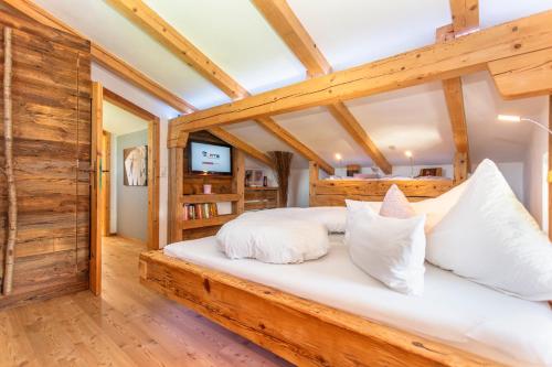 sypialnia z dużym drewnianym łóżkiem z białymi poduszkami w obiekcie Ferienwohnung Maisonette Höttl w mieście Saalfelden am Steinernen Meer