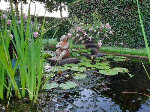 a garden with a statue sitting on a stool next to a pond at Casa di Fiore in Ospel