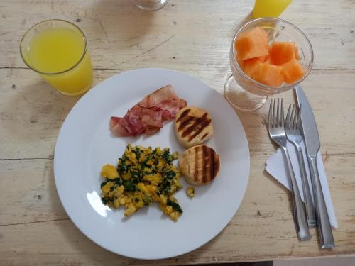 un plato blanco con desayuno y un vaso de zumo de naranja en Hotel SEREMA, en Cartagena de Indias