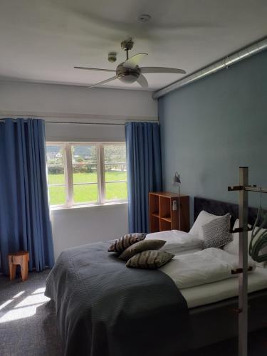 a bedroom with a bed with blue curtains and a fan at Eidfjord Adventure hotel Øvre Eidfjord in Eidfjord