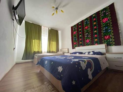 a bedroom with a bed with a blue comforter at Agropensiune Turistica Maria in Isverna
