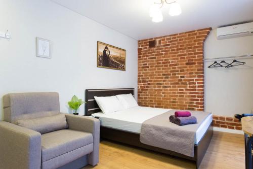 a bedroom with a bed and a chair and a brick wall at Cozy studio in the city center - Mayakovskogo str. 5-1 in Kharkiv