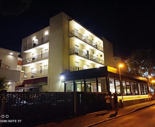 Un edificio di notte con persone che ci stanno davanti di Hotel Garisenda B&B - in Centro a Riccione - a Riccione